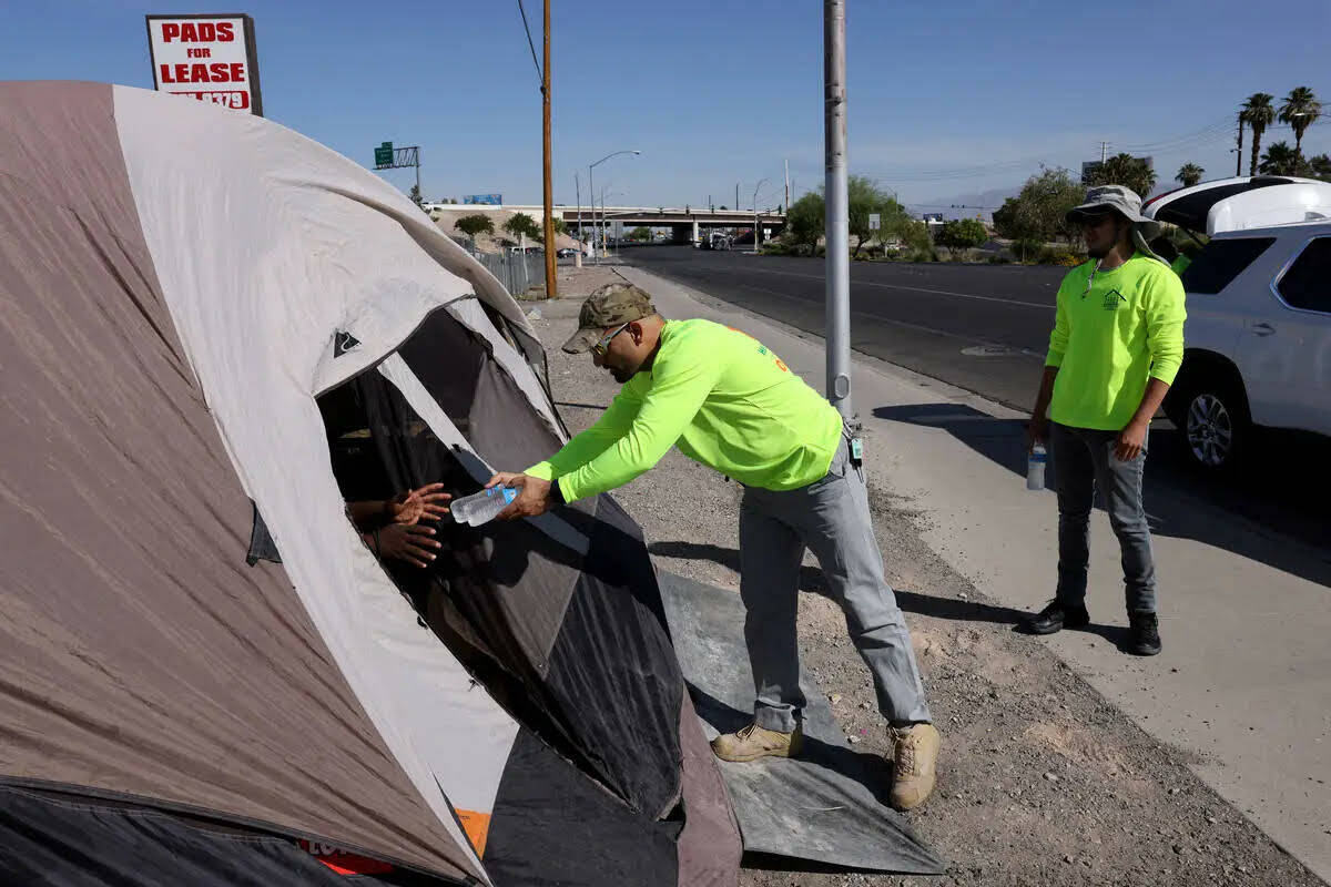 Abdul Hamdard, de HELP of Southern Nevada, ofrece agua a una persona que se refugia en una tien ...