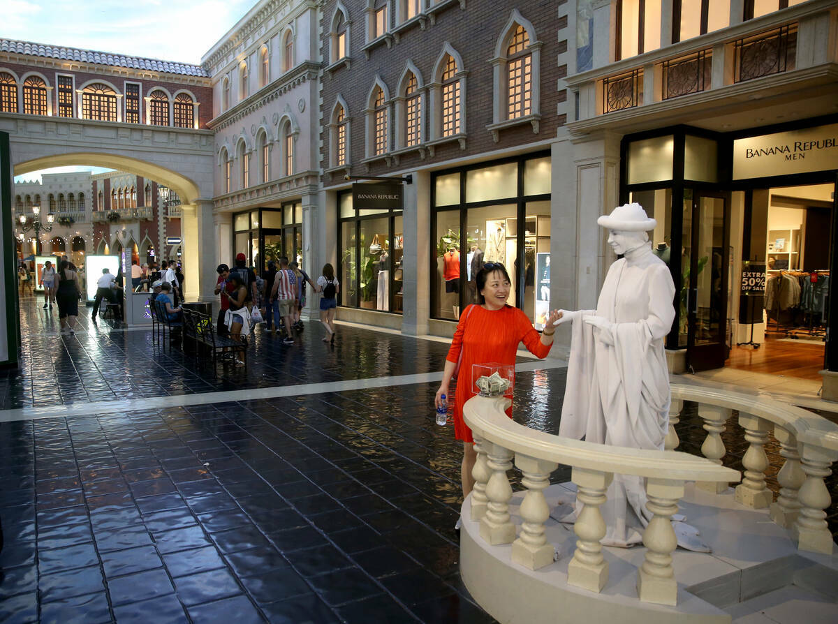 Judy Guo de Canadá saluda a una estatua viviente en The Venetian en el Strip en Las Vegas, el ...