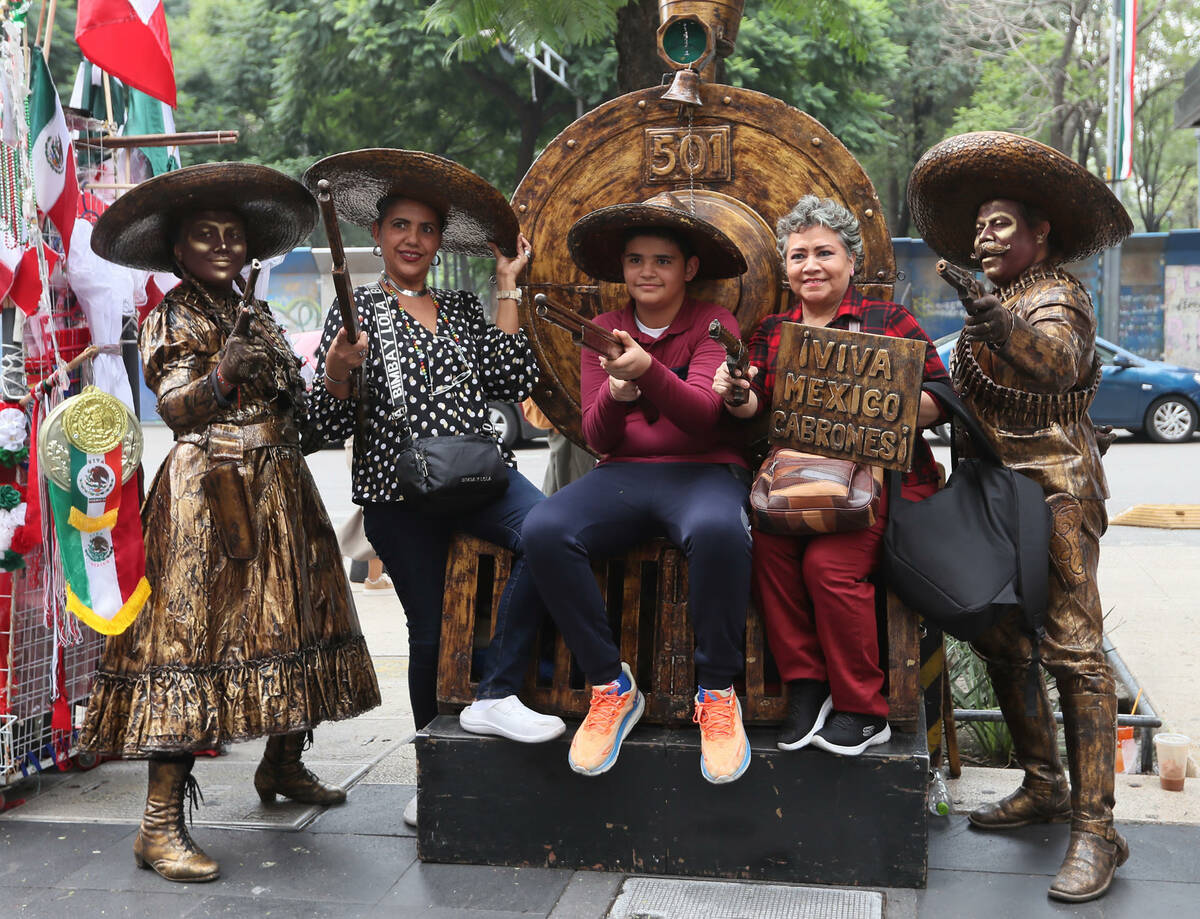 Personas se toman fotos con hombres y mujeres disfrazados con trajes alusivos a los festejos pa ...