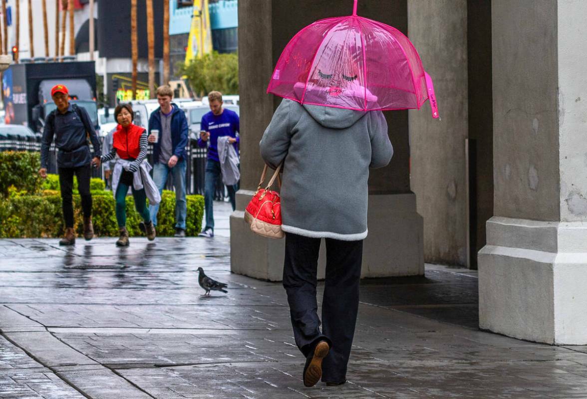 Una mujer camina con un paraguas por el Strip cerca del Caesars Palace durante un día lluvioso ...