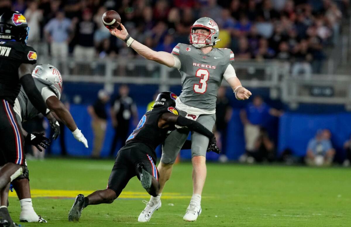 El quarterback de la UNLV Matthew Sluka (3) pasa el balón mientras es golpeado por el cornerba ...