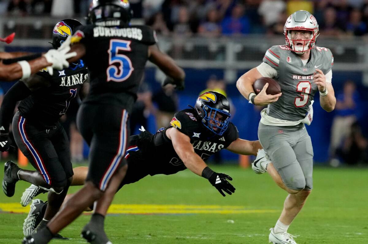 El quarterback de la UNLV Matthew Sluka (3) supera al defensive end de Kansas Dylan Wudke (95) ...