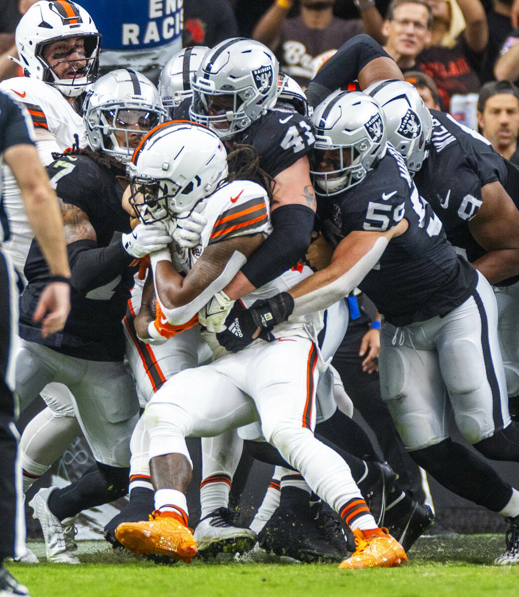 El running back de los Cleveland Browns D'Onta Foreman (27) es tacleado por un grupo de defensi ...