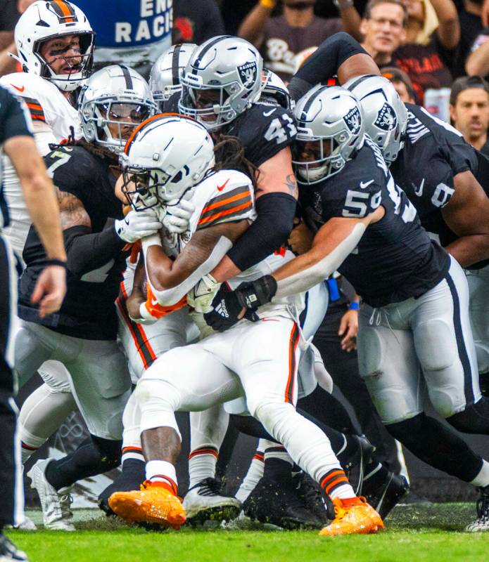 El running back de los Cleveland Browns D'Onta Foreman (27) es tacleado por un grupo de defensi ...