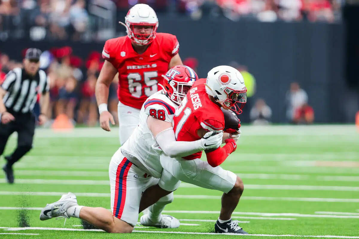 El wide receiver de UNLV, Jacob De Jesús (21), lleva el balón mientras el linebacker de Utah ...