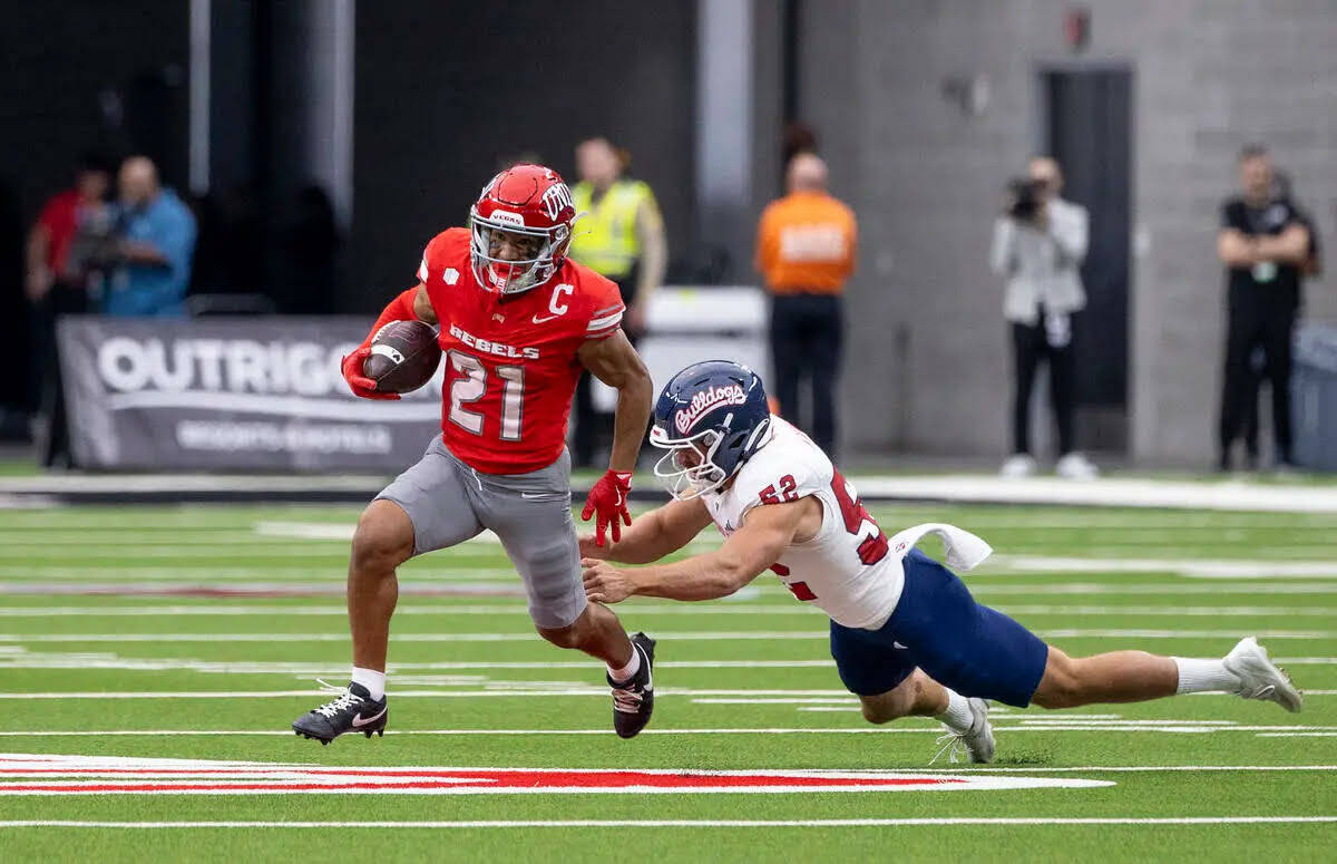 El wide receiver de UNLV, Jacob De Jesús (21), esquiva al defensive lineman de Fresno State, I ...