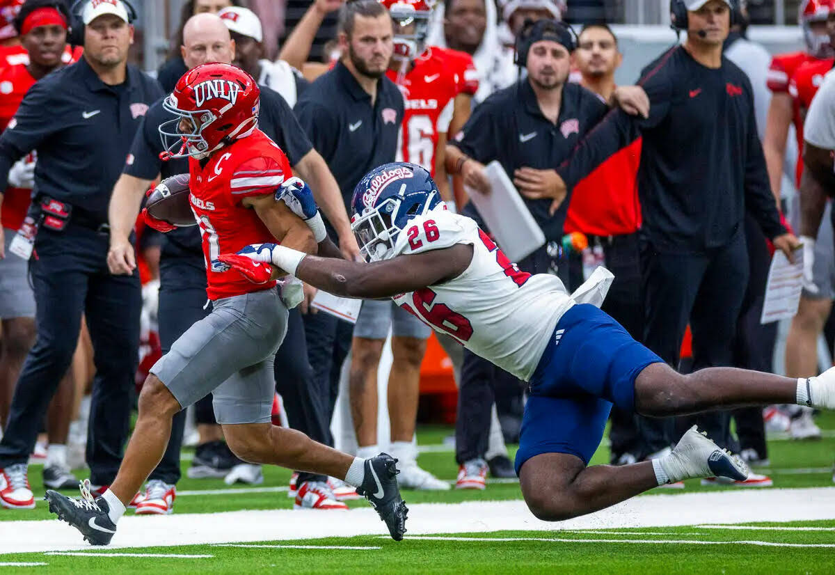 El wide receiver de UNLV, Jacob De Jesús (21), es sacado del campo por el linebacker de Fresno ...