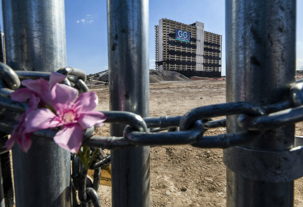 Flores dejadas en la cadena que asegura una entrada de construcción con la Club Tower al fondo ...