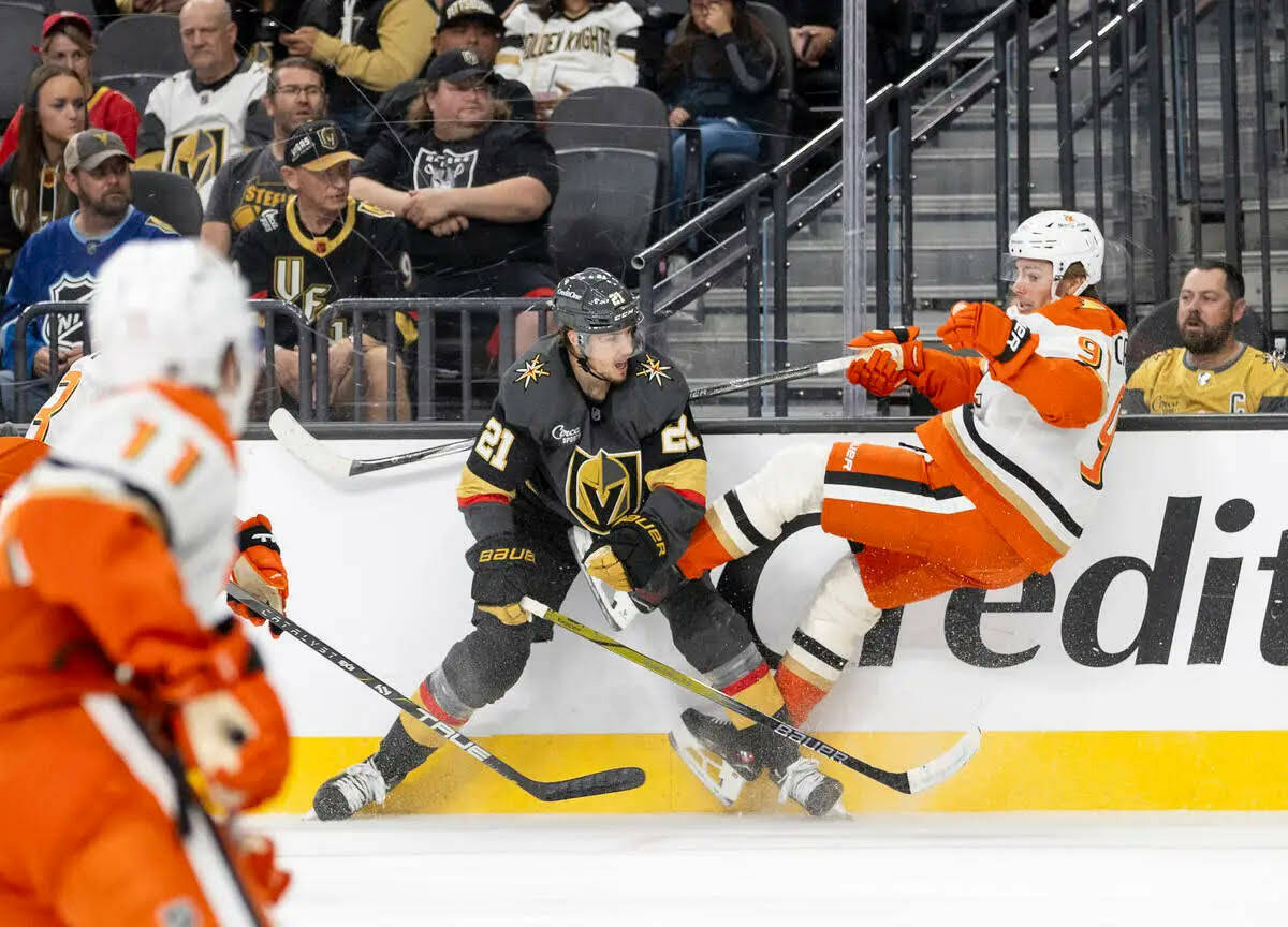 El center de los Golden Knights, Brett Howden (21), golpea al center de los Anaheim Ducks, Leo ...