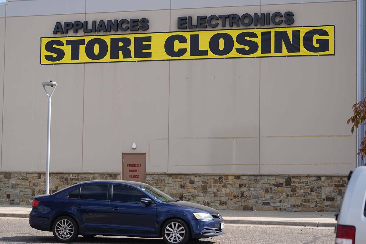 Un letrero de cierre de tienda cuelga en la pared exterior cerca de la entrada de una tienda de ...