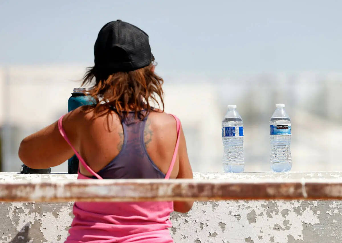 Una persona sin hogar llena su botella de agua, entregada por trabajadores de ayuda de Help of ...