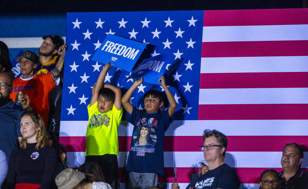 Jóvenes sostienen carteles mientras el expresidente Barack Obama habla en nombre de la campañ ...