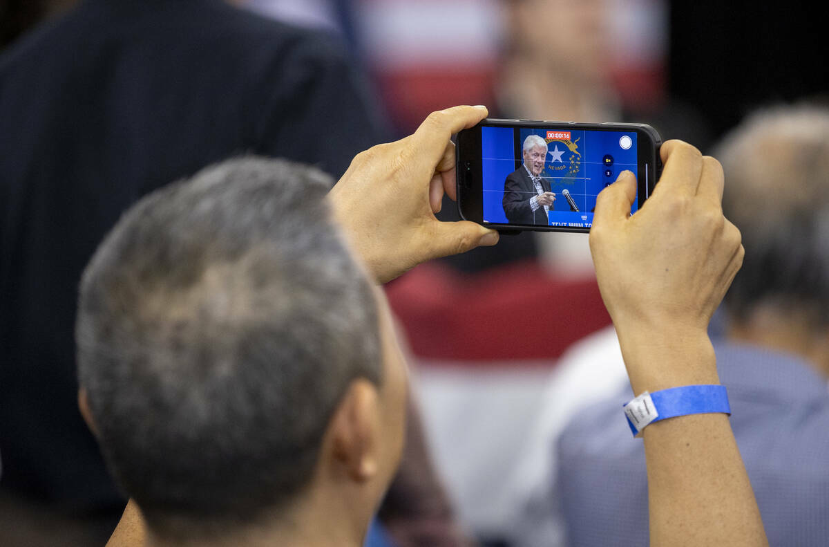 Un asistente graba al expresidente Bill Clinton durante una parada de campaña a favor de Harri ...