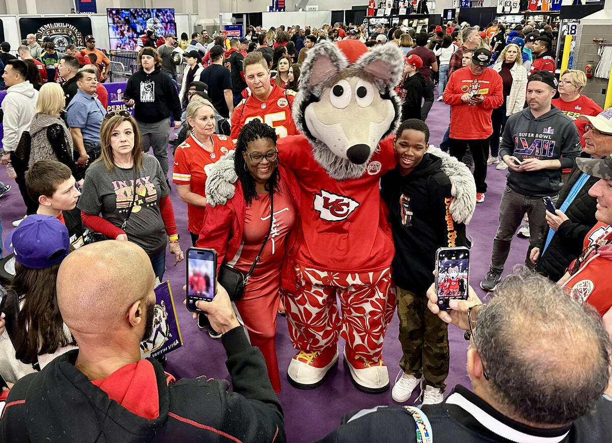 La mascota de los Kansas City Chiefs, K.C. Wolf, posa con los fanáticos de los Chiefs en el Su ...