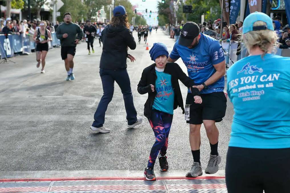 El atleta Taylor Little de Team Hoyt cruza la meta con Brian Weber durante el Maratón de Las V ...