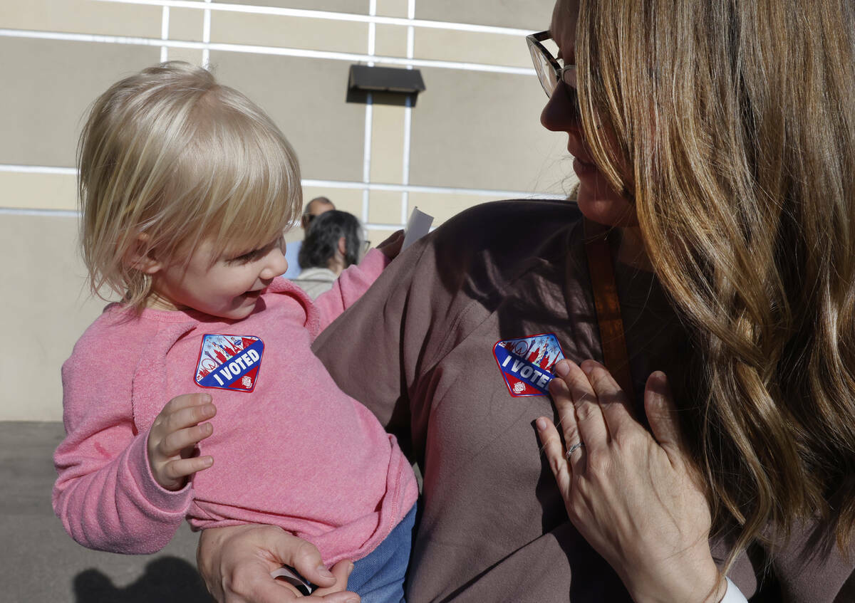 Lindsey Tiberti coloca su calcomanía de "Yo voté" en su pecho mientras su hija Maggie, de dos ...