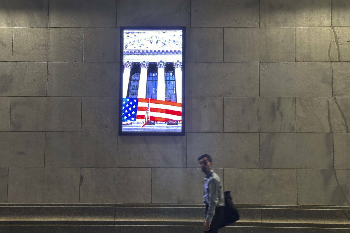 Un hombre pasa junto a un monitor de video a un costado de la Bolsa de Valores de Nueva York, e ...