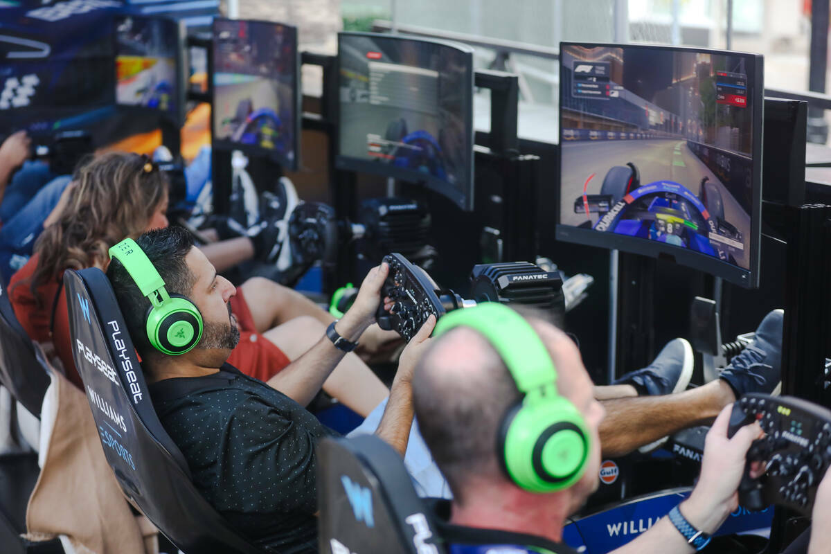 Asistentes juegan videojuegos de carreras de Fórmula 1 en la Williams Racing Fanzone, un pop-u ...