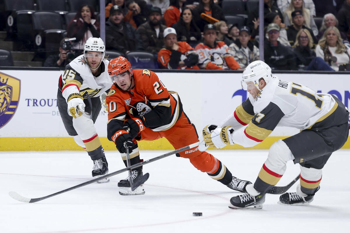 El ala derecha de los Anaheim Ducks, Brett Leason, en el centro, pasa el puck más allá del de ...