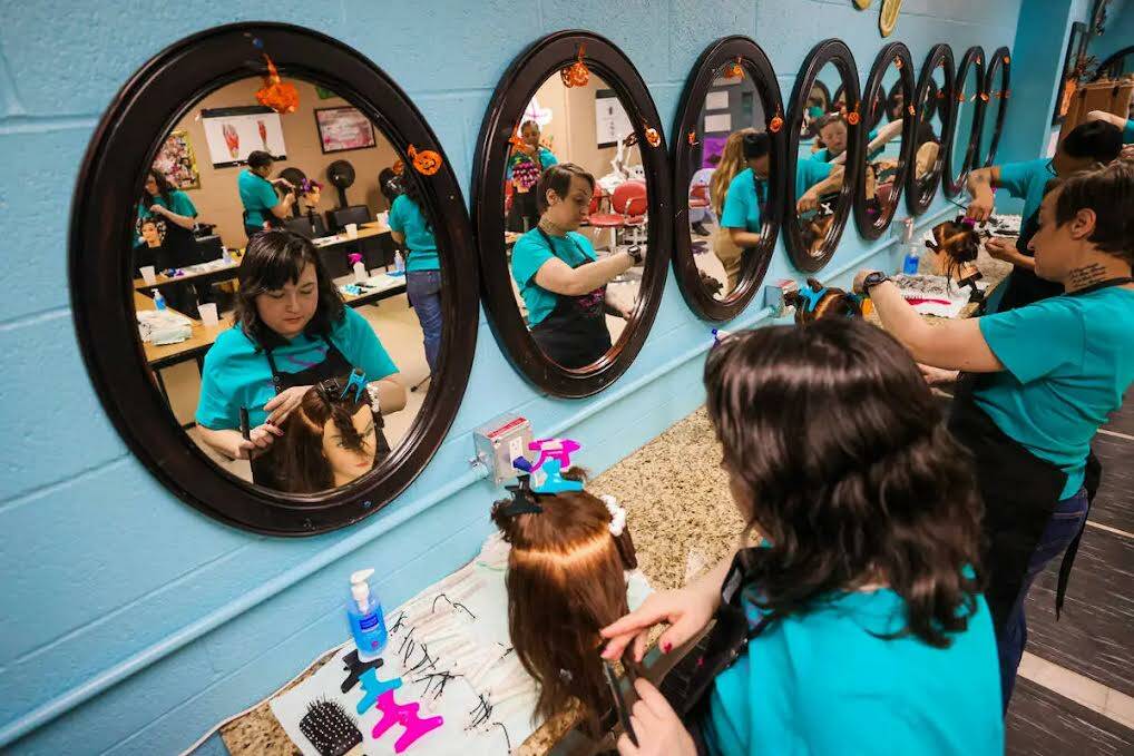 Estudiantes practican permanentes en maniquíes durante una clase de cosmetología en el Centro ...