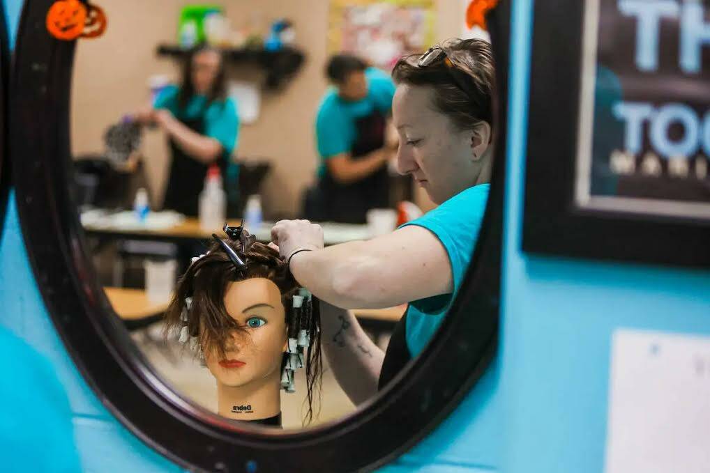 Estudiantes practican permanentes en maniquíes durante una clase de cosmetología en el Centro ...