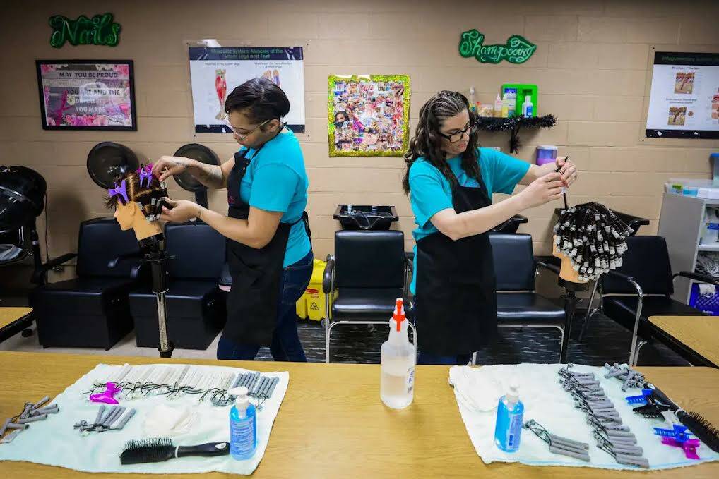 Lishae Macfield (izquierda) y Marlee Mathews practican permanentes en maniquíes durante una cl ...