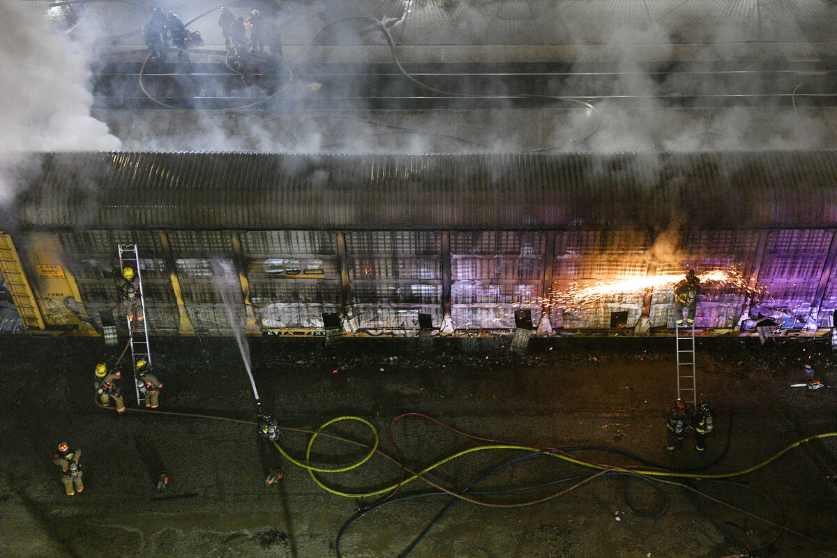 Bomberos trabajan para apagar un incendio en un vagón que transportaba automóviles el viernes ...