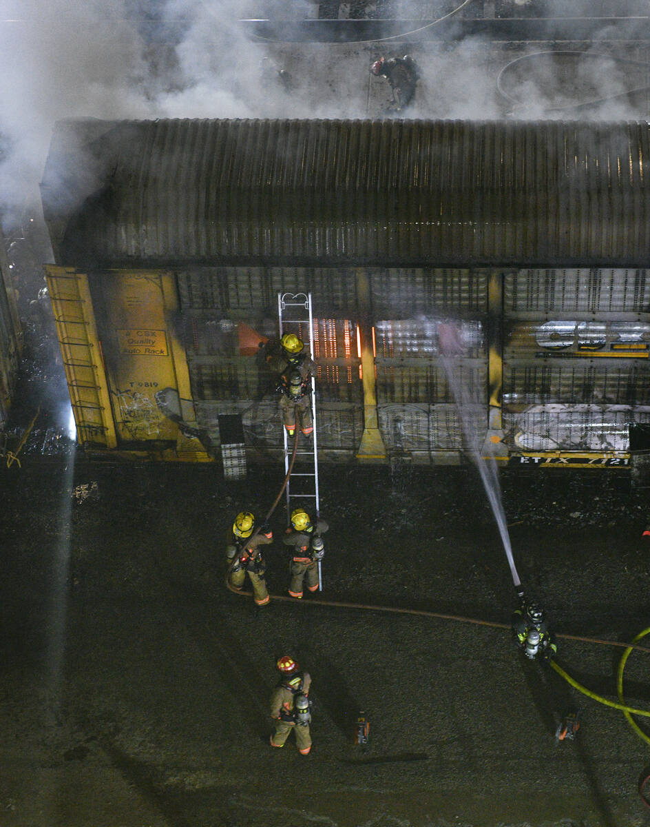 Bomberos trabajan para apagar un incendio en un vagón que transportaba automóviles el viernes ...