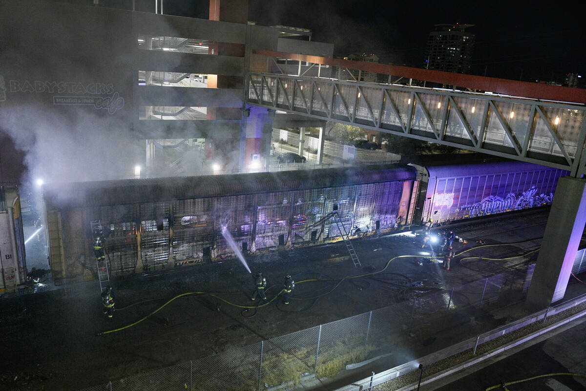 Bomberos trabajan para apagar un incendio en un vagón que transportaba automóviles el viernes ...