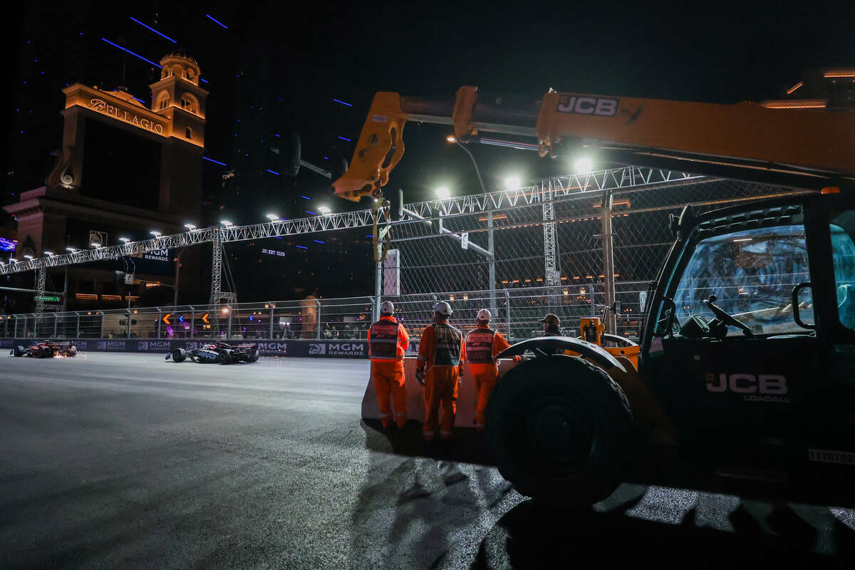 Trabajadores de la Fórmula 1 observan a los pilotos pasar a toda velocidad durante el Gran Pre ...