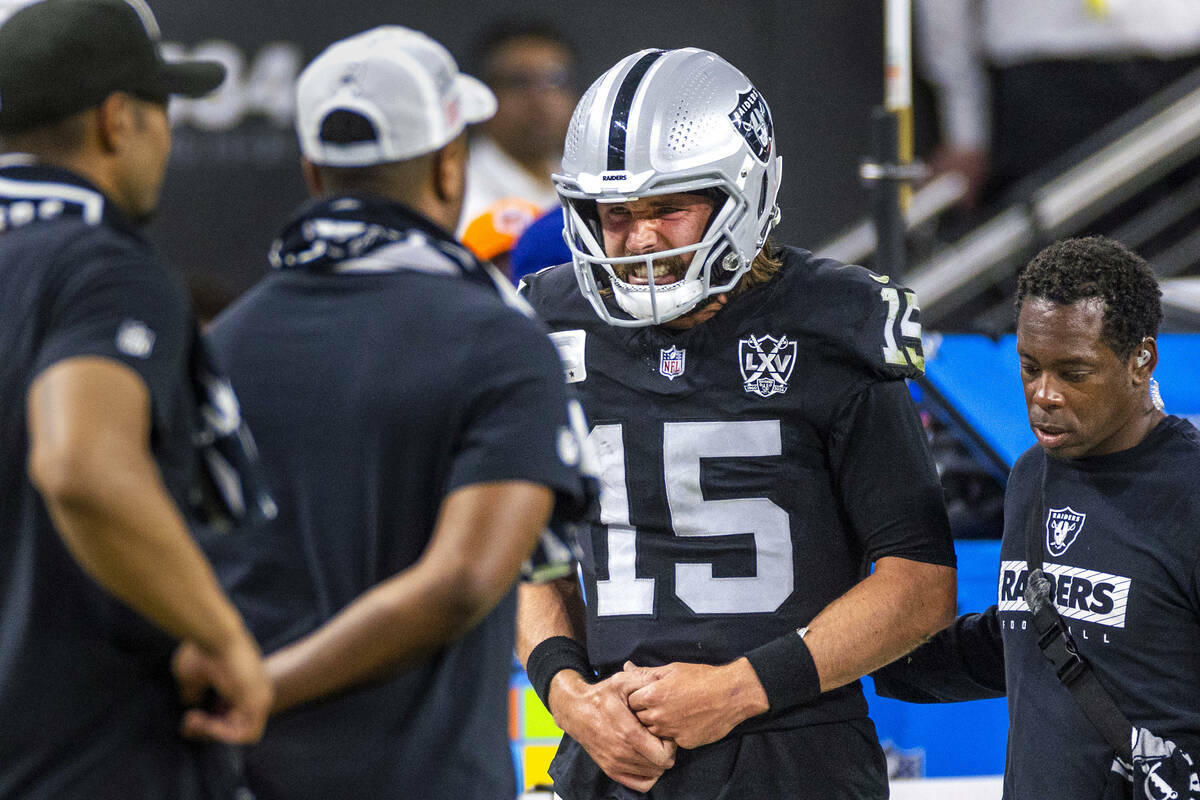 El quarterback de los Raiders Gardner Minshew (15) es escoltado fuera del campo después de un ...