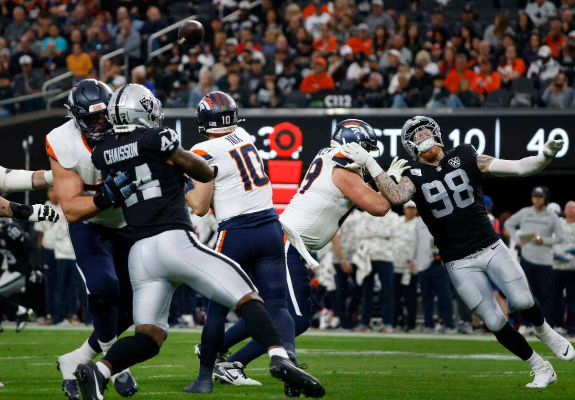 El quarterback de los Denver Broncos Bo Nix (10) lanza bajo la presión del defensive end K'Lav ...