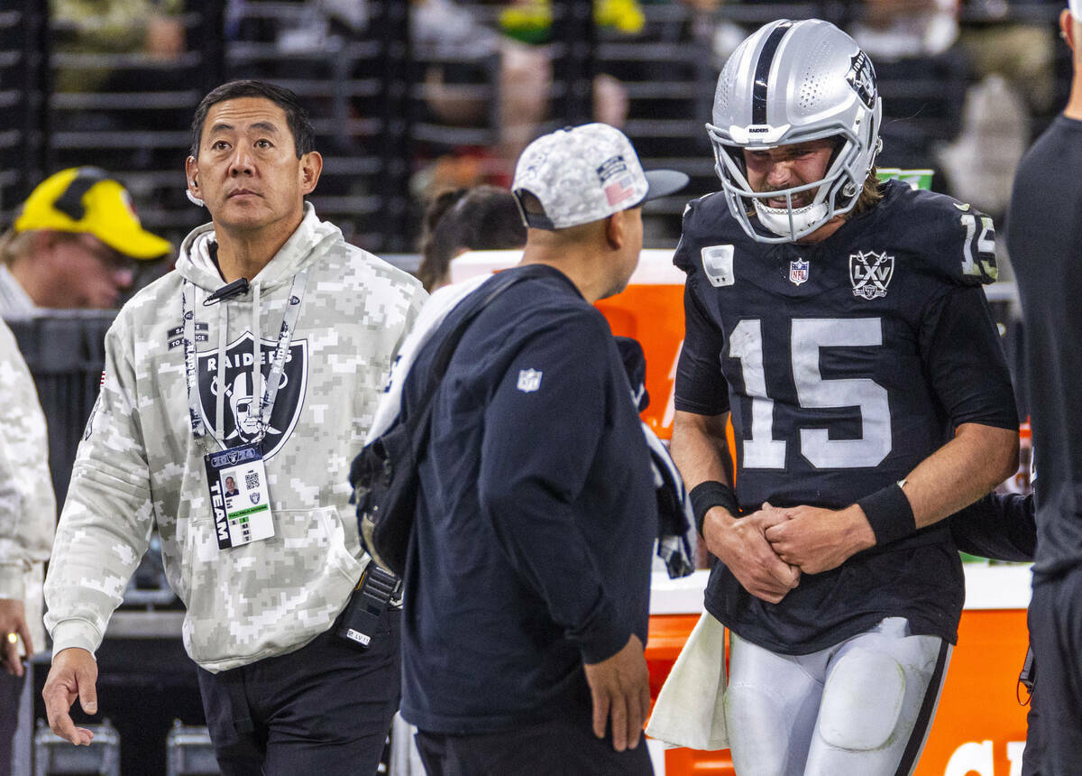 El quarterback de los Raiders Gardner Minshew (15) es escoltado fuera del campo por el cirujano ...