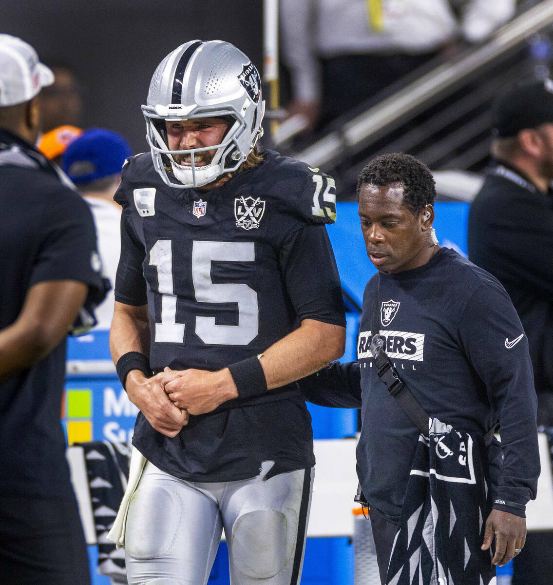 El quarterback de los Raiders Gardner Minshew (15) es escoltado fuera del campo después de un ...