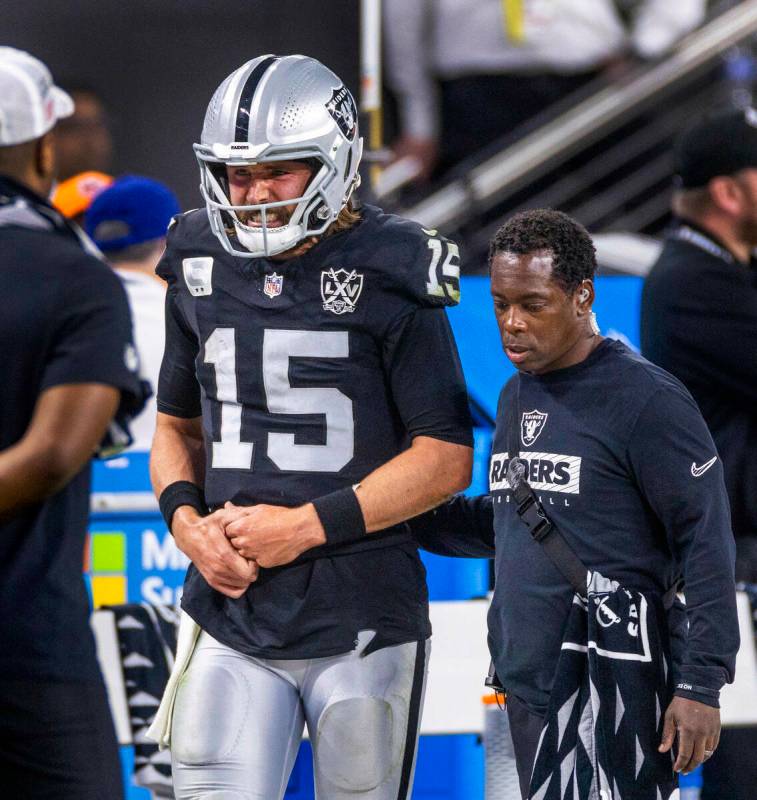 El quarterback de los Raiders Gardner Minshew (15) es escoltado fuera del campo después de un ...