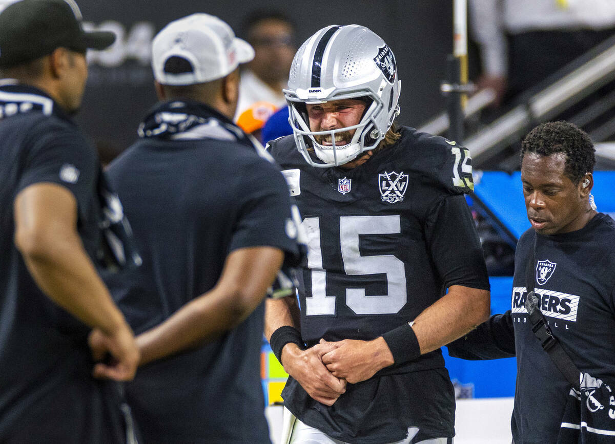 El quarterback de los Raiders Gardner Minshew (15) es escoltado fuera del campo después de un ...