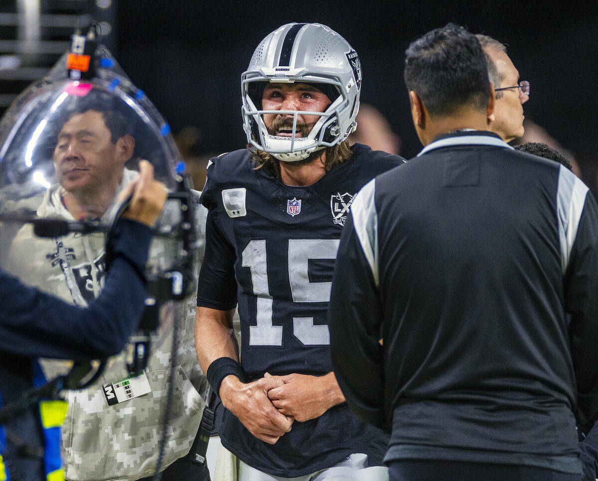 El quarterback de los Raiders Gardner Minshew (15) es escoltado fuera del campo después de un ...