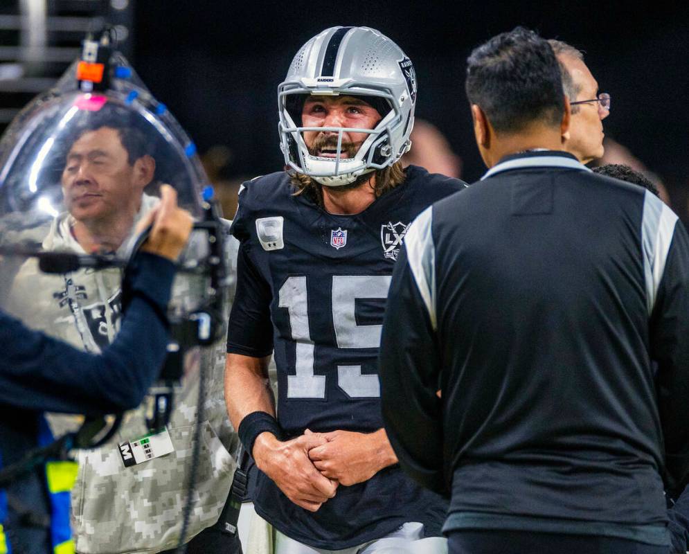 El quarterback de los Raiders Gardner Minshew (15) es escoltado fuera del campo después de un ...