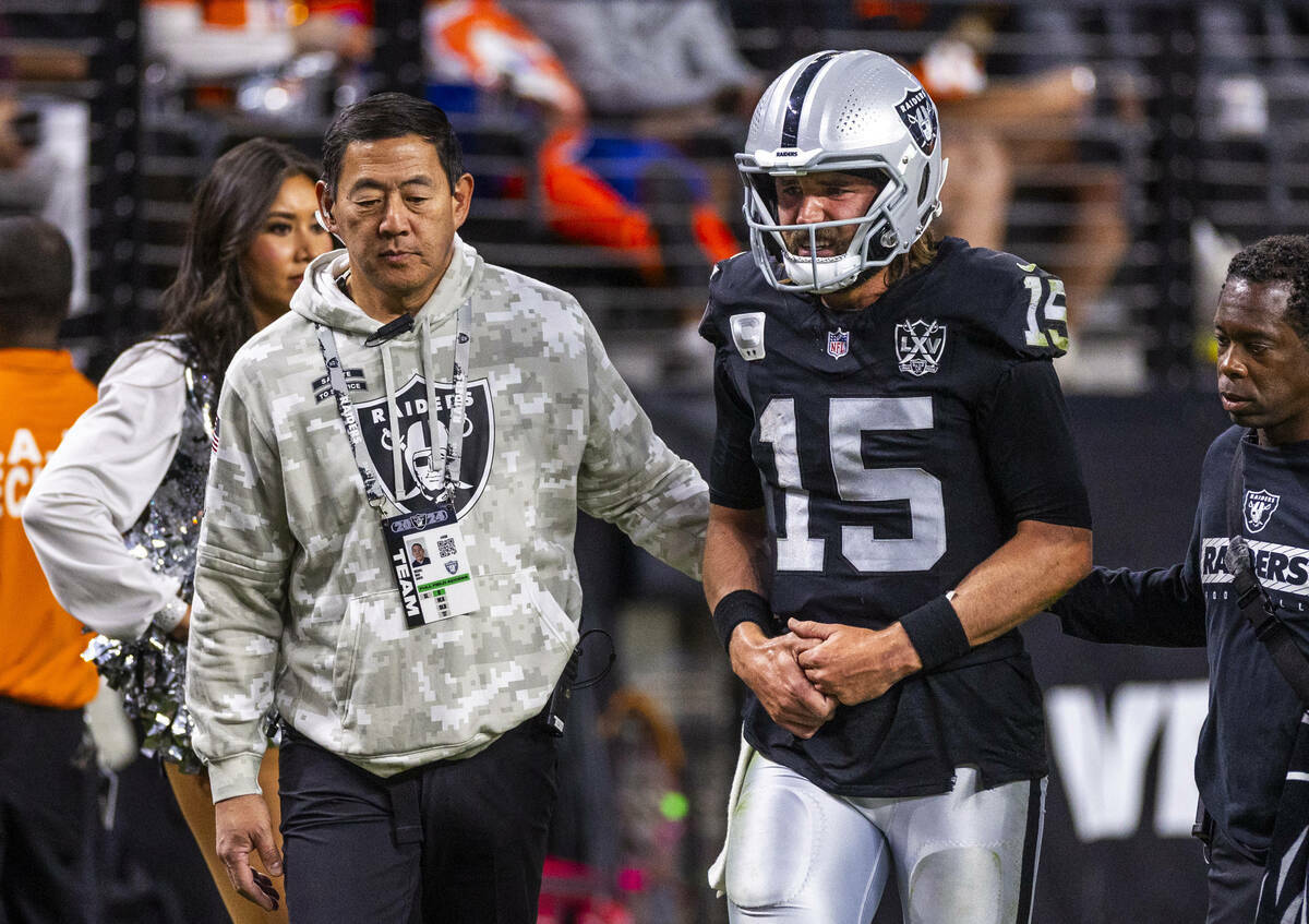 El quarterback de los Raiders Gardner Minshew (15) es escoltado fuera del campo por el cirujano ...