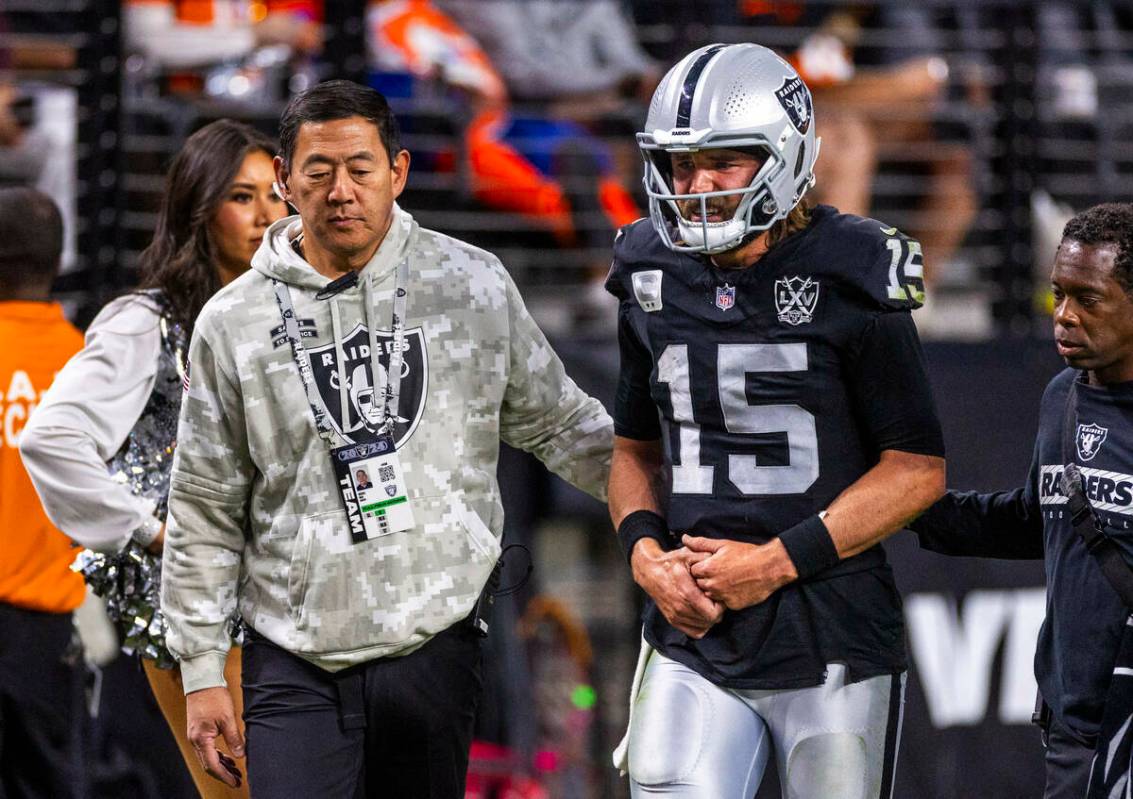 El quarterback de los Raiders Gardner Minshew (15) es escoltado fuera del campo por el cirujano ...