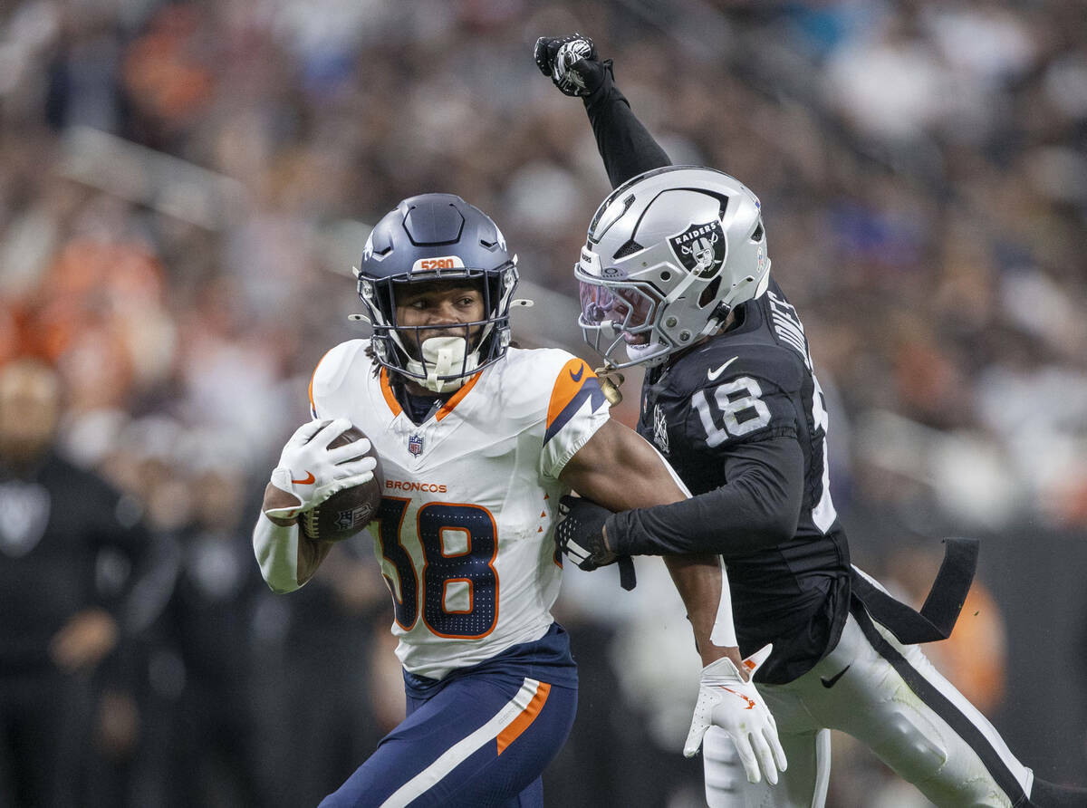 El cornerback de los Raiders Jack Jones (18) intenta quitar el balón de las manos del running ...