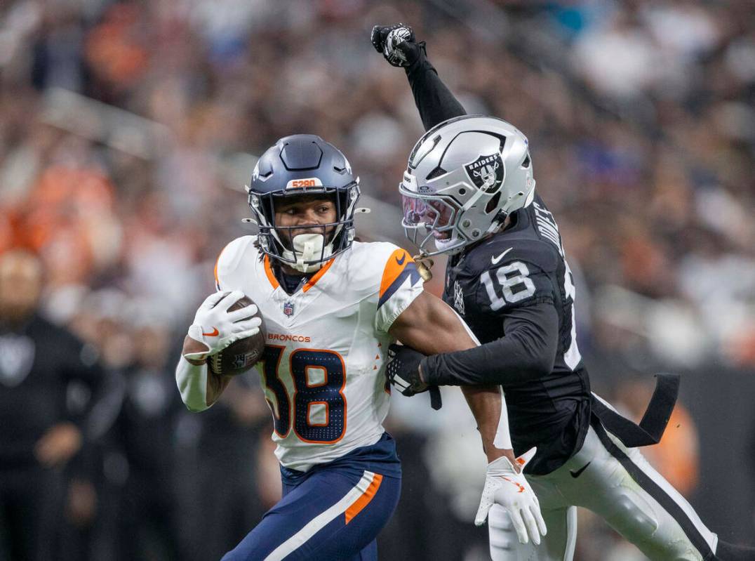 El cornerback de los Raiders Jack Jones (18) intenta quitar el balón de las manos del running ...