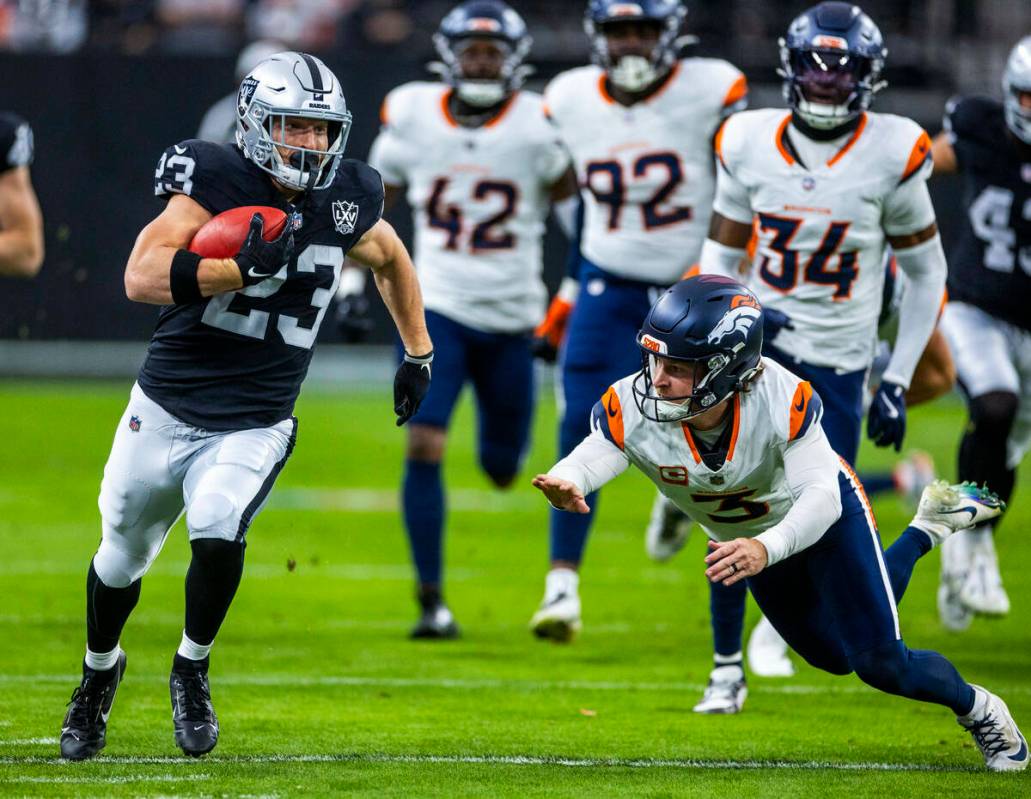 El running back de los Raiders Dylan Laube (23) casi supera al pateador de los Denver Broncos W ...