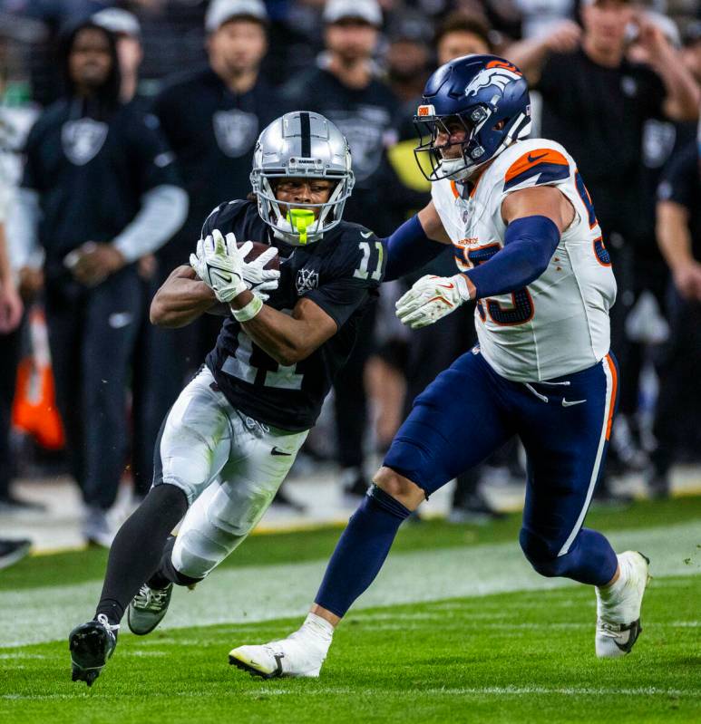 El wide receiver de los Raiders Tre Tucker (11) asegura un pase mientras el linebacker de los D ...