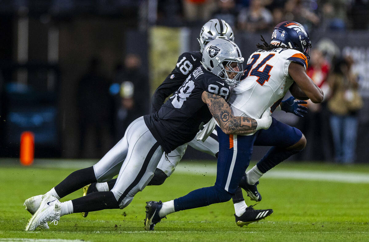 El defensive end de los Raiders Maxx Crosby (98) detiene al wide receiver de los Denver Broncos ...