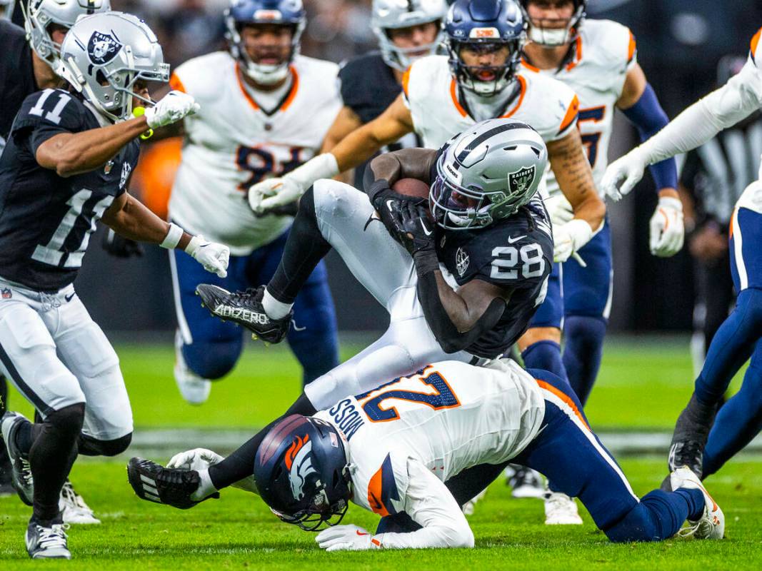 El running back de los Raiders Sincere McCormick (28) es frenado en carrera por el cornerback d ...