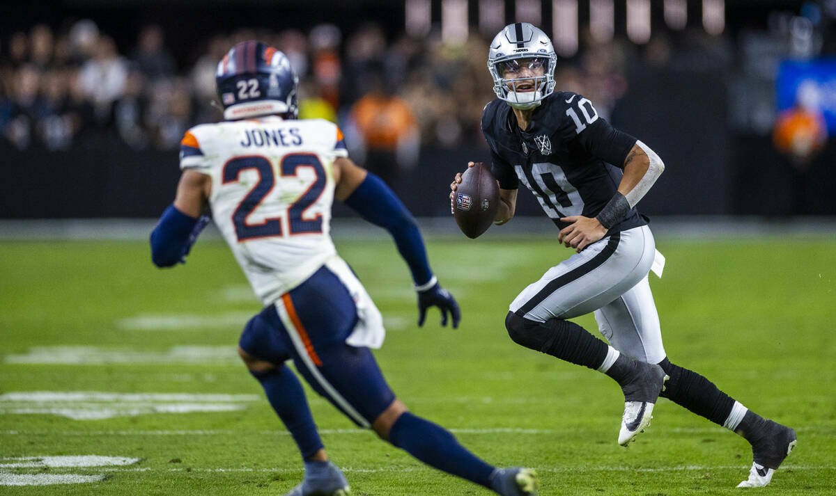 El quarterback de los Raiders Desmond Ridder (10) intenta un pase mientras el defensa de los De ...