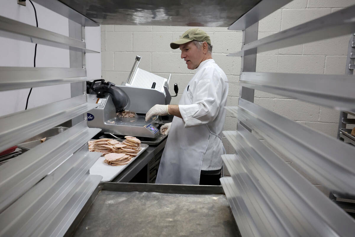 El sous chef Neil Mockovak prepara rebanadas de pavo para 700 comidas de Thanksgiving en Cathol ...