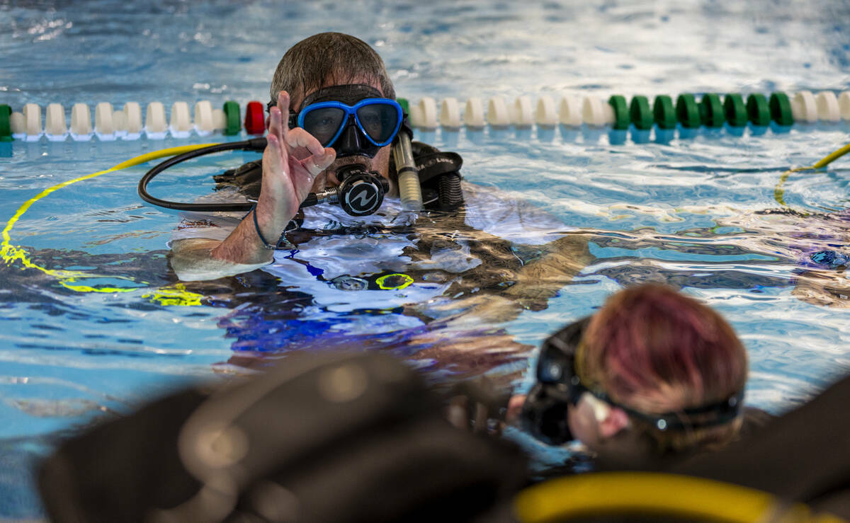 El instructor de buceo de Sin City Scuba Curtis Snaper muestra señales de mano para usar bajo ...