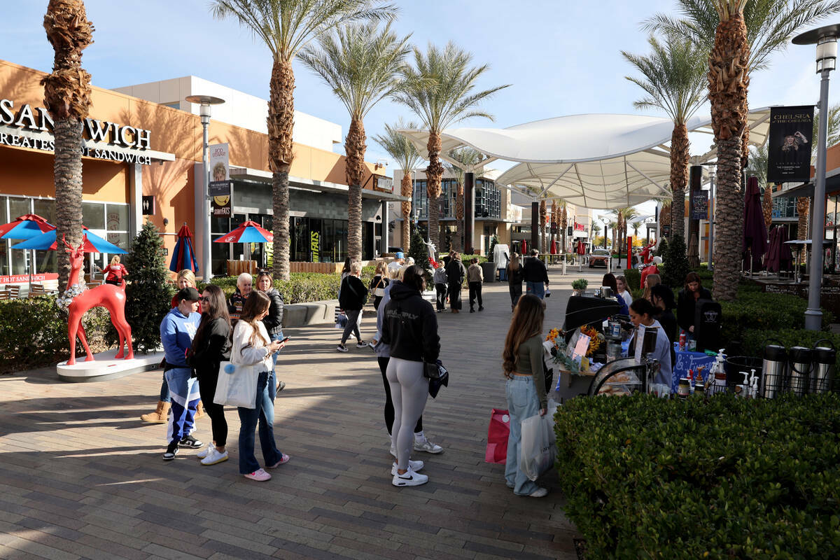 Personas hacen fila para tomar un café mientras hacen compras el Black Friday en el centro de ...